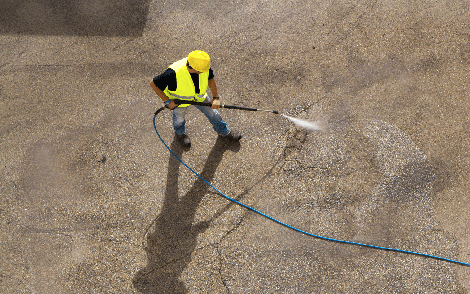 A man in a yellow vest is using a hose