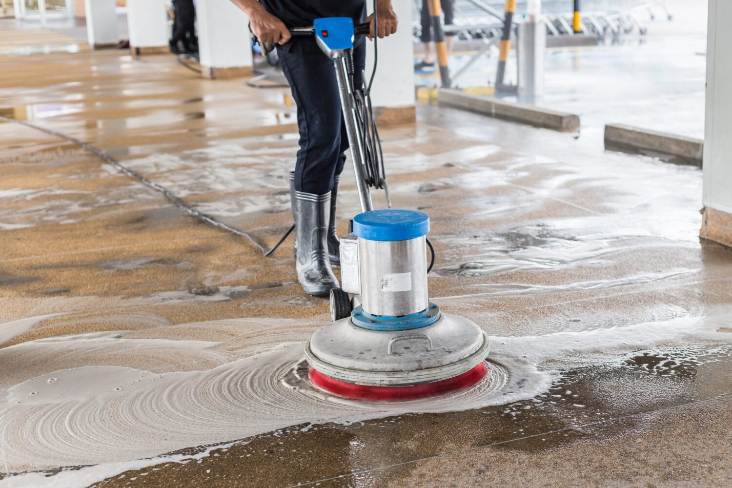 A janitor cleaning sand wash exterior walkway using polishing machine and chemical or acid